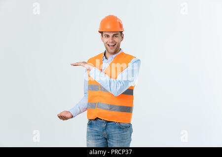 Happy beard engineer holding hand on side and explaining something, guy wearing caro shirt and jeans with yellow vest and orange helmet, isolated on white background Stock Photo