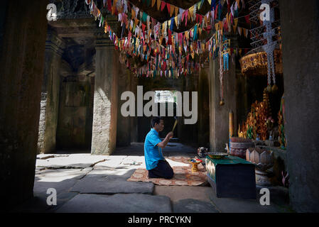 Man praying with incenses inside temple in Angkor Wat. The Angkor Wat complex, Built during the Khmer Empire age, located in Siem Reap, Cambodia, is t Stock Photo