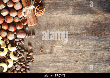 Different nuts on a wooden table. Cedar, cashew, hazelnut, walnuts and a spoon on the table. Many nuts are inshell and chistchenyh on a wooden backgro Stock Photo