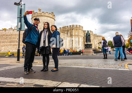 A tourist Asian family pose for a selfie taken with a mobile phone in front of Windsor Castle  in Windsor, UK Stock Photo