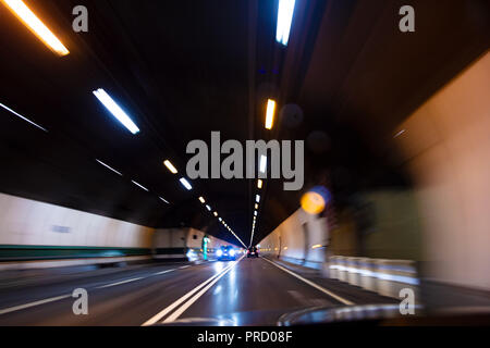 Motion blur driving a car at speed through a road tunnel at night Stock Photo