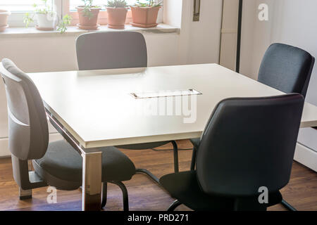 four empty chairs in a conference room with a white table Stock Photo