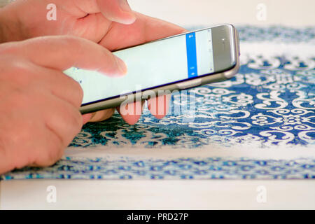 Male hand checking mail using a smartphone by touching the screen with fingers Stock Photo