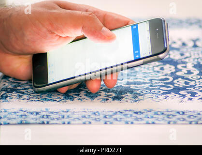 Male hand checking mail using a smartphone by touching the screen with fingers Stock Photo