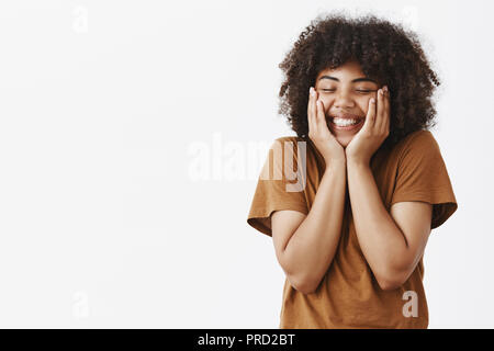 Pleased african america woman in love feeling excitement and affection being uplifted and touched after great date in romantic place holding hands on face closing eyes and smiling broadly Stock Photo