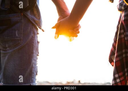 Young couple in love walking in the autumn park holding hands looking in the sunset Stock Photo