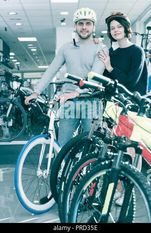 Portrait of  man and  female  in helmet standing with bicycle in the store Stock Photo