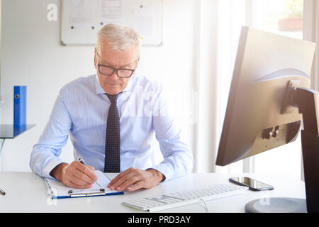 Portrait of senior bank officer sitting in his office and sign the contract. Stock Photo