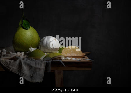 The fresh pomelo company with peeled one and the pomelo flesh on the wooden plate in light painting style Stock Photo