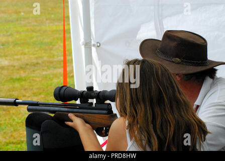 Close up of a young girl being taught to shoot a rifle. Please note- The people are not recognizable. Stock Photo