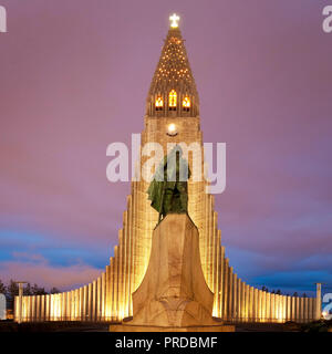 Illuminated Hallgrímskirkja with statue of Leif Eriksson at dusk, Reykjavik, Iceland Stock Photo