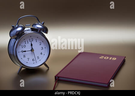 Alarm clock and notebook on gold background, For time concept. Stock Photo