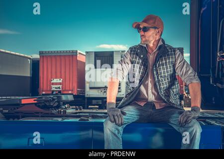 https://l450v.alamy.com/450v/prdenw/truck-driver-rest-area-parking-for-truckers-caucasian-men-taking-break-and-seating-on-his-semi-tractor-prdenw.jpg