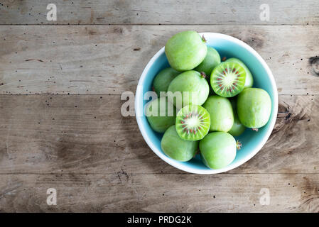 hardy kiwi fruits or kiwi berries in ceramic bowl on table Stock Photo