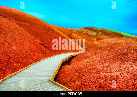 Boardwalk between mounds of Textured claystone, part of the Painted Cove Trail in the Painted Hills Unit of the John Day Fossil Bed National Monument  Stock Photo