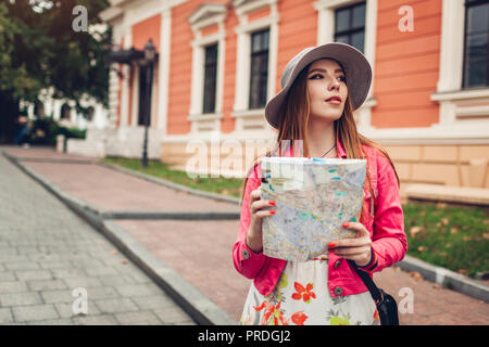 Young woman tourist searching for right way using map in Odessa, Ukraine. Girl lost in city. Traveler walking and going sightseeing Stock Photo