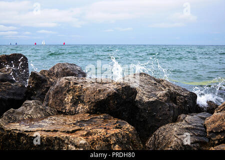 In the background, there are many bright colored sails on the sea horizon. They are seen through the Small Splash. The streams of water froze in the a Stock Photo