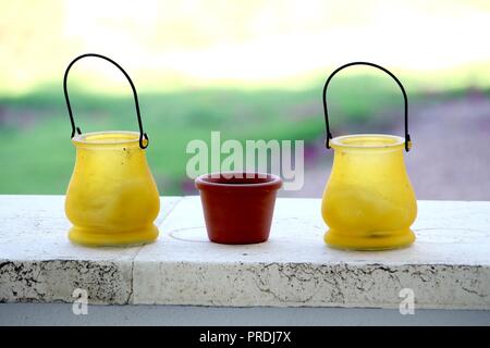 Small yellow and terracotta pots, on a stone ledge, with bright out of focus background Stock Photo
