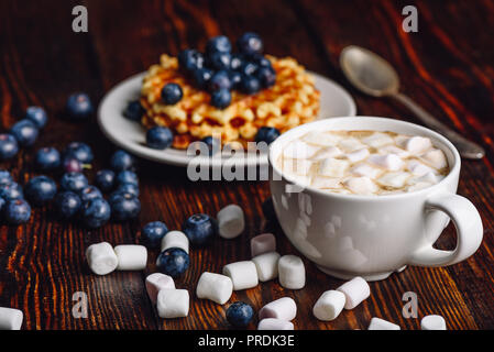 Cup of Hot Chocolate with Marshmallow with Belgian Waffles on Plate with Fresh Blueberry. Spoon and Some Berries and Marshmallows Scattered on Wooden  Stock Photo