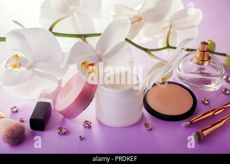 Set of natural cosmetics and make-up brushes with white orchid on pink background Stock Photo