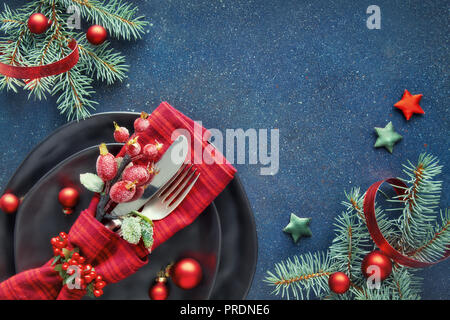 Xmas decorations in red and blue with Christmas tree twigs, including spoon and fork in decorated napkin with text space Stock Photo