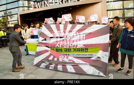 Protest against Japanese rising sun flag in South Korea, Oct 1, 2018 : South Korean activists from civic groups cut a mock Japanese rising sun flag during a press conference in front of the Japanese embassy in Seoul, South Korea. The protesters criticized Japan and its navy planning to display Japanese Rising Sun Flag, which protesters think as a symbol of wartime aggression, during the International Fleet Review to be held off the island of Jeju, South Korea from October 10-14. Navy ships from 15 countries including Japan, China and the U.S. will participate in the event. South Korean navy sa Stock Photo