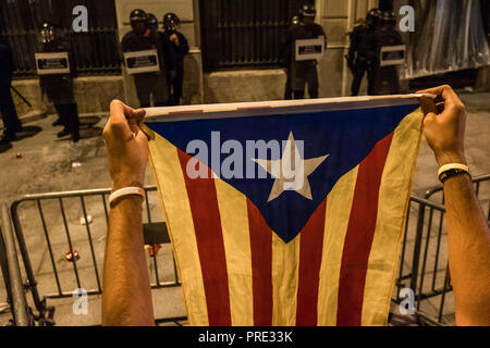 Barcelona, Catalonia, Spain. 1st Oct, 2018. A protester is seen showing a pro-independence flag to the police officers who protect the police station.Thousands of pro-independence protesters from Catalonia have participated in the anniversary march of the 1-O. At the end of the demonstration hundreds of people gathered in front of the Police station until the police push them away. Credit: Paco Freire/SOPA Images/ZUMA Wire/Alamy Live News Stock Photo