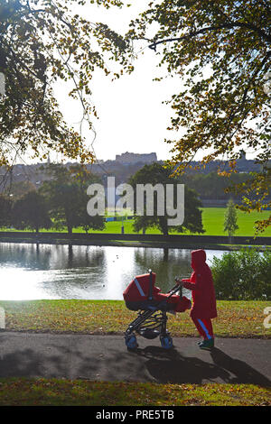 Edinburgh, Inverleith Park, Scotland, UK. 2nd Oct, 2018. Weather, sunny with 11 degrees and 19 km/h winds with Gusts of 28km/h from the north, people wrapped up against the cold while walking in the park, the autumn colours have arrived earlier than usual but leaves are blowing off the branches due to recent stormy winds. Stock Photo
