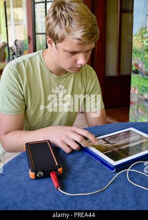 Recharging with solar powered Bigfoot Solar Power Bank from ToughTested, used to recharge iPad tablet or other mobile cell smart phones, from CES, USA Stock Photo