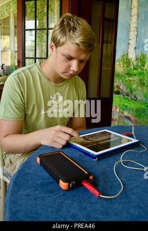 Recharging with solar powered Bigfoot Solar Power Bank from ToughTested, used to recharge iPad tablet or other mobile cell smart phones, from CES, USA Stock Photo