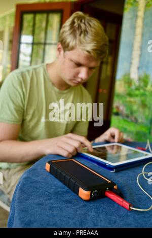 Recharging with solar powered Bigfoot Solar Power Bank from ToughTested, used to recharge iPad tablet or other mobile cell smart phones, from CES, USA Stock Photo