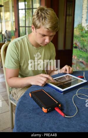 Recharging with solar powered Bigfoot Solar Power Bank from ToughTested, used to recharge iPad tablet or other mobile cell smart phones, from CES, USA Stock Photo