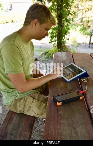 Recharging with solar powered Bigfoot Solar Power Bank from ToughTested, used to recharge iPad tablet or other mobile cell smart phones, from CES, USA Stock Photo