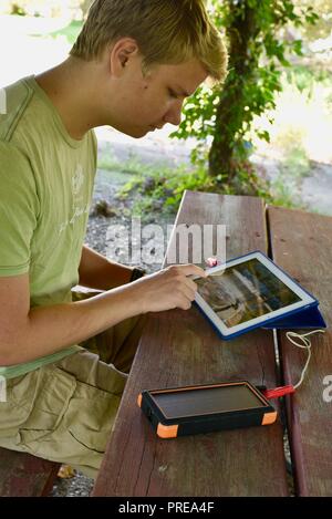 Recharging with solar powered Bigfoot Solar Power Bank from ToughTested, used to recharge iPad tablet or other mobile cell smart phones, from CES, USA Stock Photo