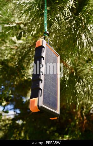 Recharging with sun light, hanging in tree, Bigfoot Solar Power Bank from ToughTested, used to recharge tablet or mobile cell smart phones, at CES USA Stock Photo