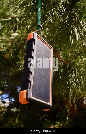 Recharging with sun light, hanging in tree, Bigfoot Solar Power Bank from ToughTested, used to recharge tablet or mobile cell smart phones, at CES USA Stock Photo