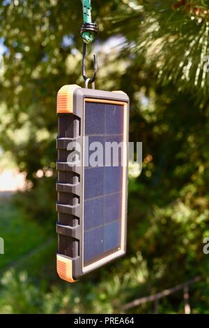 Recharging with sun light, hanging in tree, Bigfoot Solar Power Bank from ToughTested, used to recharge tablet or mobile cell smart phones, at CES USA Stock Photo