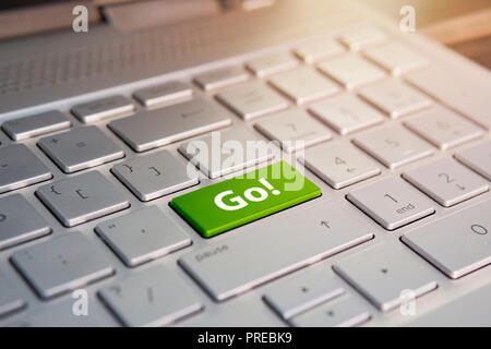 word go written on a green computer keyboard key or button. Color button on the gray silver keyboard of modern ultrabook. caption on the button Stock Photo
