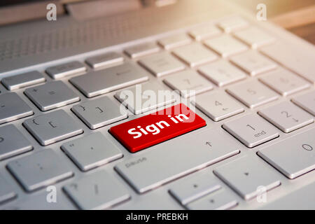 Signing up. gesture of finger pressing sign up now button on a computer keyboard. Red Color button on the gray silver keyboard of modern ultrabook. SI Stock Photo