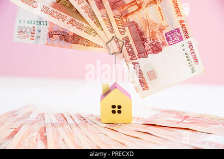 Model of the house standing on five thousand banknotes.Rental estate.Sale property template.Model of wooden house with money. House building, loan,real estate, cost of housing or buying a new home concept. Stock Photo