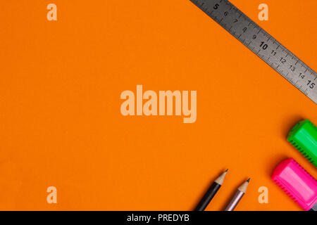 Two pencils, one ruler and two markers lie on orange background. Top view. Stock Photo