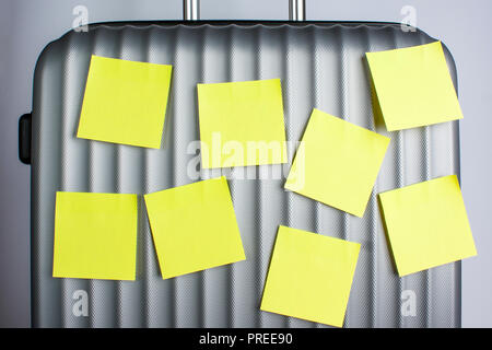 Gray suitcase for travel with eight yellow stickers on a gray background Stock Photo