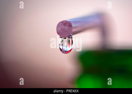A water drop is dripping from a pipette Stock Photo