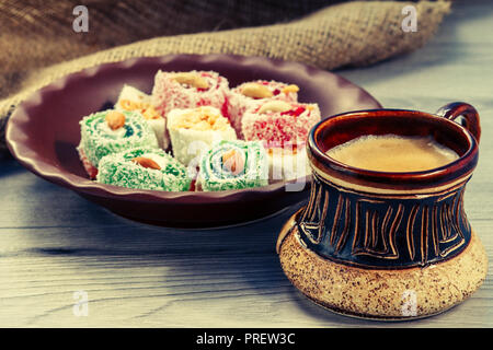 Clay cup of coffee and Turkish delight lying on clay plate on wooden board with piece of sackcloth Stock Photo