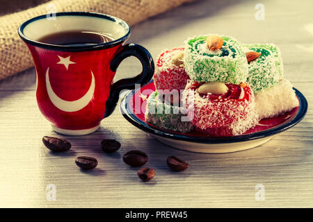 Cup of coffee with coffee beans and Turkish delight lying on saucer on wooden board with piece of sackcloth Stock Photo