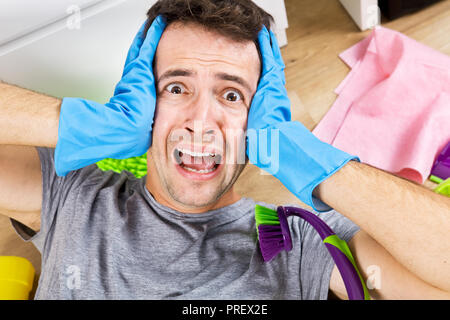 Frustrated young man holding cleaning equipment. Cleaning time Stock Photo