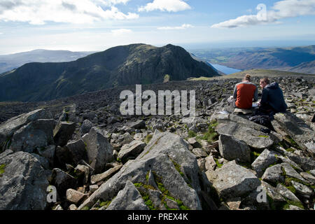 Walkers on Scafell Pike summit looking towards Scafell Stock Photo