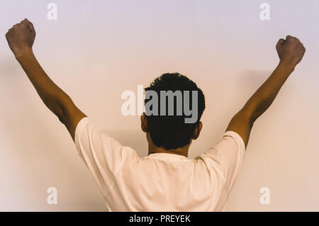 Studio shot of modern hipster young man with hands up, back view. isolated on white background Stock Photo
