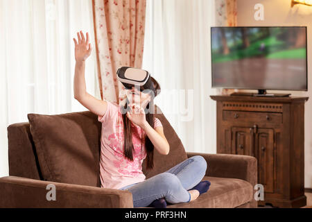 Happy teenager girl having fun with virtual reality glasses at home. People and new technology concept. Stock Photo