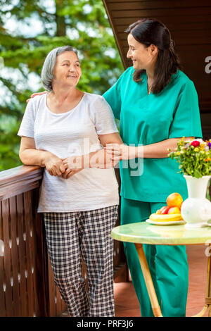 Senior woman with her home caregiver spending time together. Female nurse consoling senior woman at home. Stock Photo